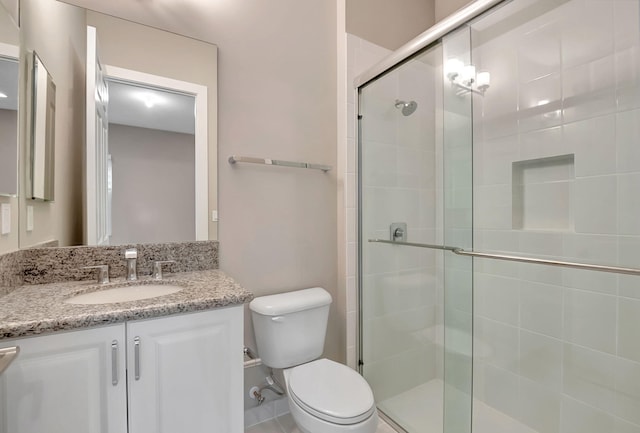 bathroom with vanity, toilet, and a shower with door