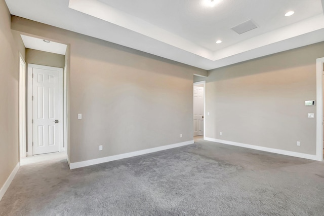 carpeted empty room with a raised ceiling