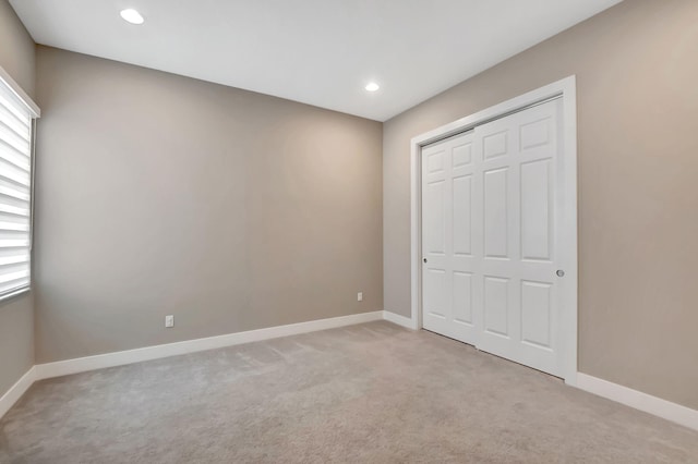 unfurnished bedroom with light colored carpet and a closet