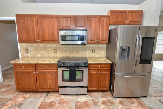 kitchen featuring stainless steel appliances, light stone counters, and tasteful backsplash