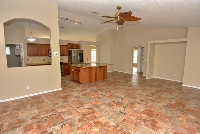 kitchen with decorative light fixtures, vaulted ceiling, stainless steel appliances, and ceiling fan