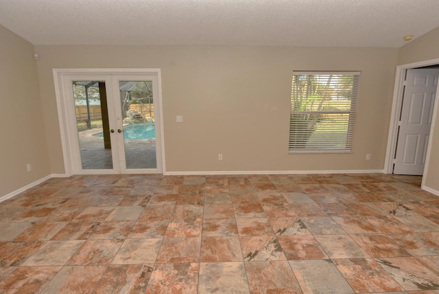 empty room with french doors and a textured ceiling