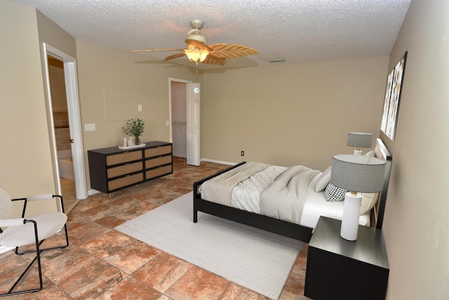 bedroom with ceiling fan, ensuite bathroom, and a textured ceiling