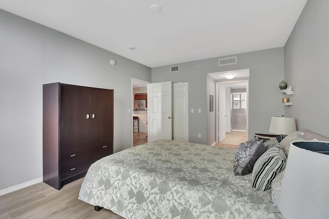 bedroom with ensuite bath and light hardwood / wood-style floors