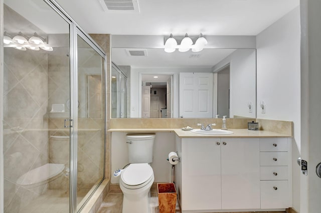 bathroom featuring tile patterned floors, vanity, toilet, and a shower with door