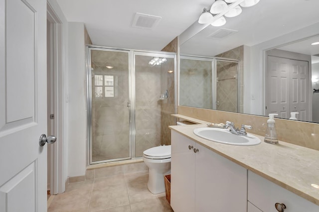 bathroom with tile patterned flooring, vanity, toilet, and a shower with door