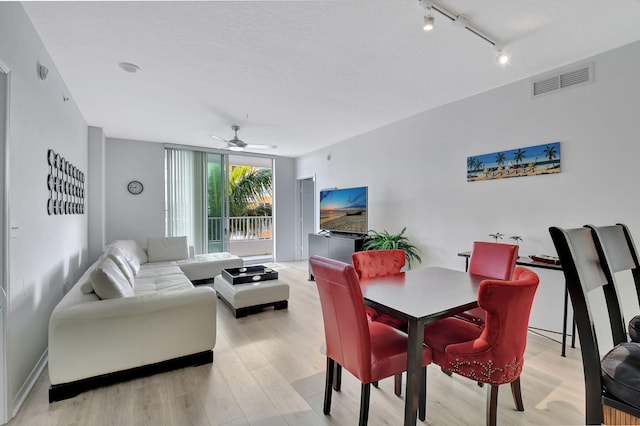 dining area featuring a textured ceiling, rail lighting, light hardwood / wood-style floors, and ceiling fan