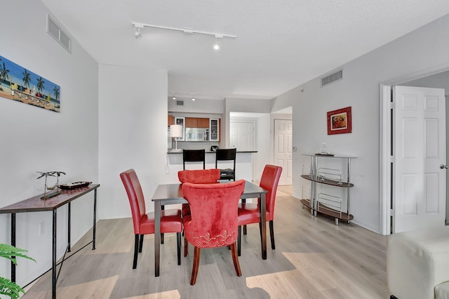 dining space featuring rail lighting and light hardwood / wood-style floors