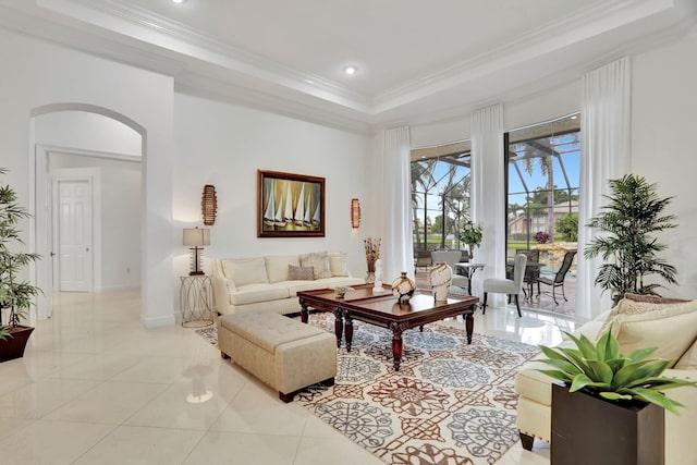 tiled living room with ornamental molding and a tray ceiling