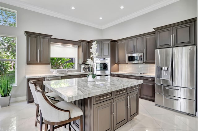 kitchen with decorative backsplash, a center island, light tile patterned floors, and appliances with stainless steel finishes