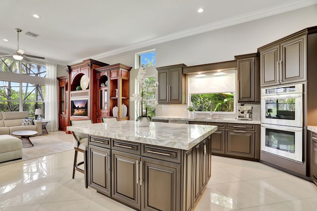 kitchen with tasteful backsplash, a kitchen island, a healthy amount of sunlight, and light tile patterned flooring