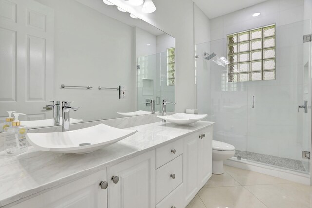 bathroom with tile patterned flooring, vanity, a shower with door, and toilet