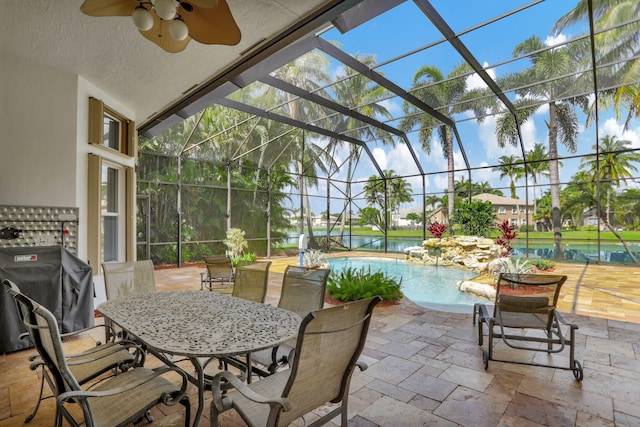 view of patio featuring a lanai, grilling area, ceiling fan, and a water view