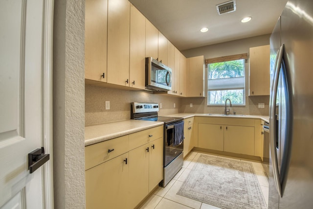 kitchen featuring appliances with stainless steel finishes, light tile patterned floors, tasteful backsplash, and sink