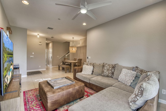 tiled living room with ceiling fan with notable chandelier