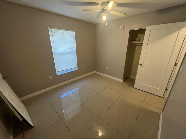 unfurnished bedroom featuring ceiling fan, a closet, and light tile patterned floors