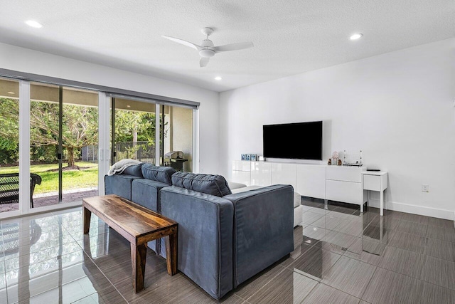 living room with ceiling fan, dark tile patterned flooring, and a textured ceiling