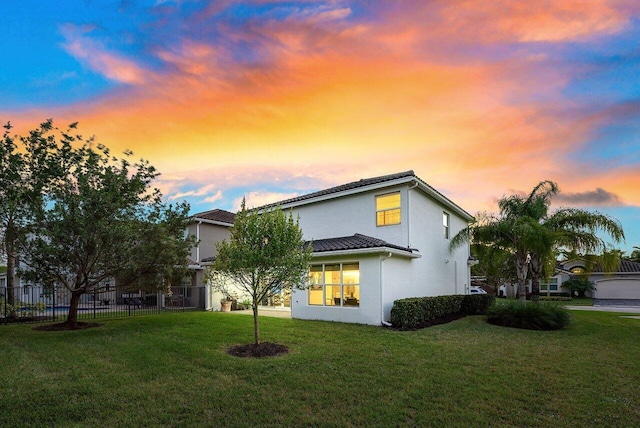 property exterior at dusk featuring a yard