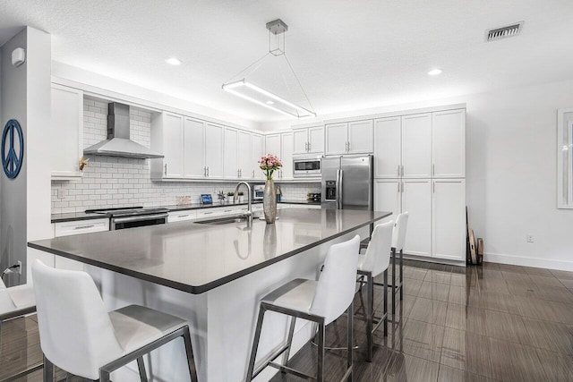 15360 Seaglass Terrace Ln, Delray Beach, FL 33446 - kitchen featuring wall chimney exhaust hood, a sink, appliances with stainless steel finishes, dark countertops, and a breakfast bar area