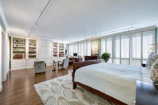 bedroom with dark hardwood / wood-style flooring, rail lighting, and crown molding