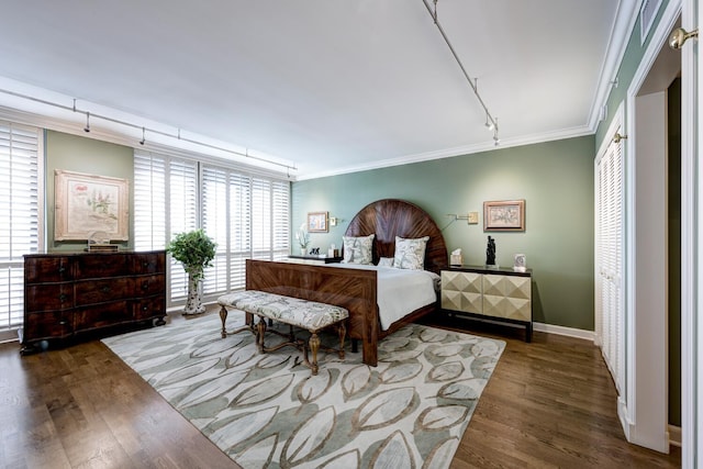 bedroom featuring crown molding, dark hardwood / wood-style flooring, and rail lighting