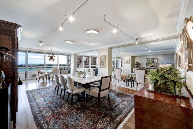 dining space featuring hardwood / wood-style floors, a water view, ornamental molding, and a wall of windows