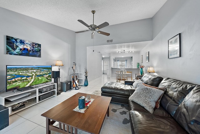 living room with lofted ceiling, ceiling fan, light tile patterned floors, and a textured ceiling