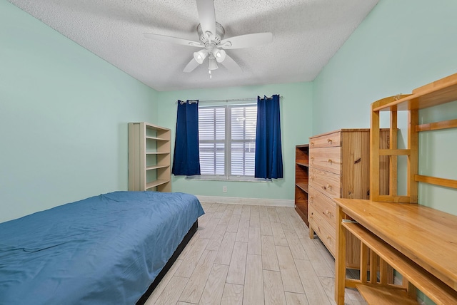 bedroom with a textured ceiling, light wood-type flooring, and ceiling fan