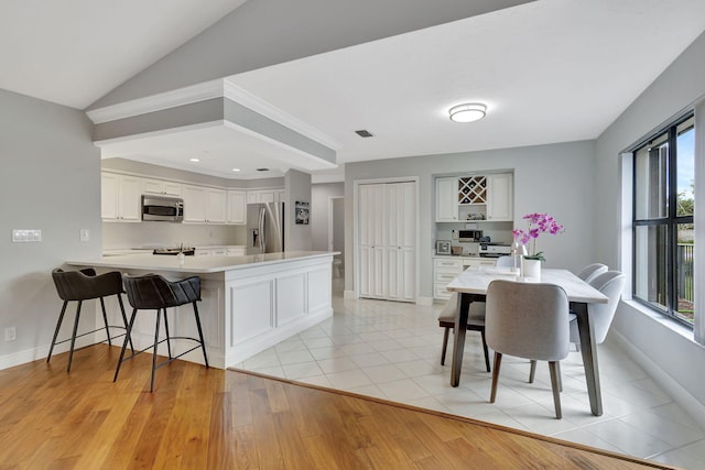 kitchen featuring a healthy amount of sunlight, white cabinetry, stainless steel appliances, and light hardwood / wood-style flooring