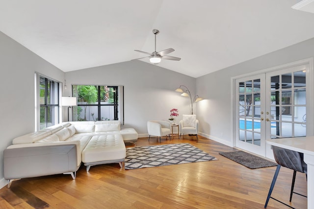 living room featuring ceiling fan, french doors, vaulted ceiling, and light wood-type flooring