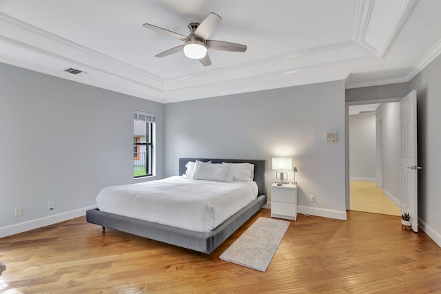 bedroom featuring a tray ceiling, light hardwood / wood-style flooring, ceiling fan, and crown molding