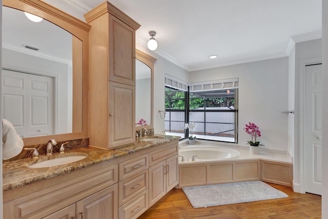 bathroom featuring a tub, vanity, ornamental molding, and hardwood / wood-style flooring