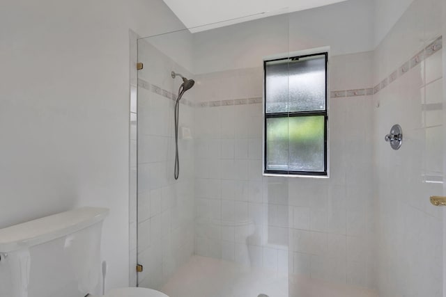 bathroom with tiled shower and toilet