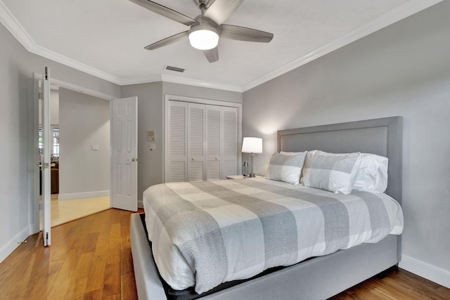 bedroom with ceiling fan, a closet, wood-type flooring, and ornamental molding