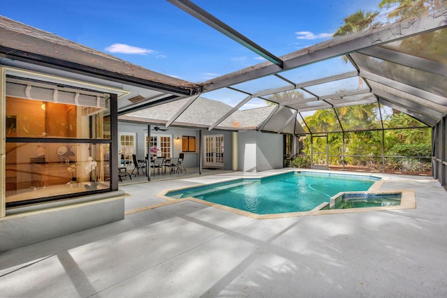 view of swimming pool featuring a patio area, ceiling fan, glass enclosure, and an in ground hot tub