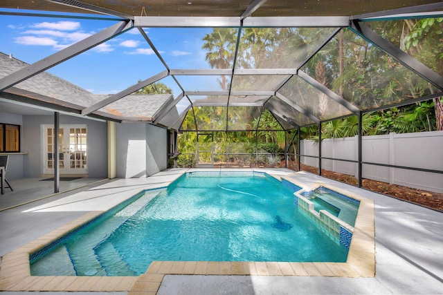 view of swimming pool with glass enclosure, a patio area, an in ground hot tub, and french doors