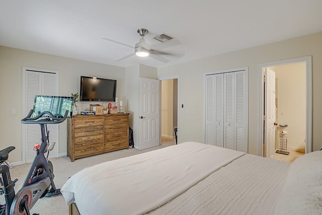 bedroom with ceiling fan, light colored carpet, and two closets