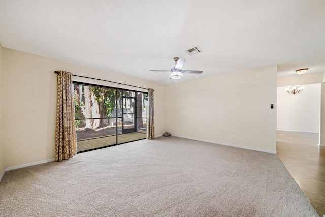 carpeted spare room featuring ceiling fan with notable chandelier