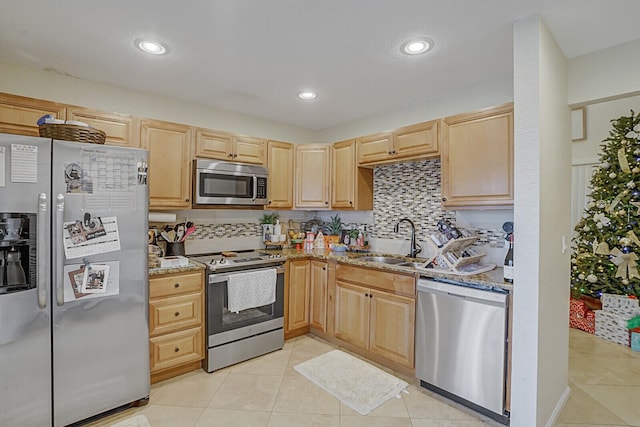 kitchen with light stone countertops, sink, light brown cabinets, backsplash, and appliances with stainless steel finishes