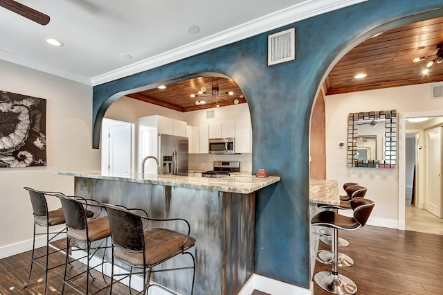 kitchen featuring appliances with stainless steel finishes, light stone counters, dark wood-type flooring, wooden ceiling, and white cabinets