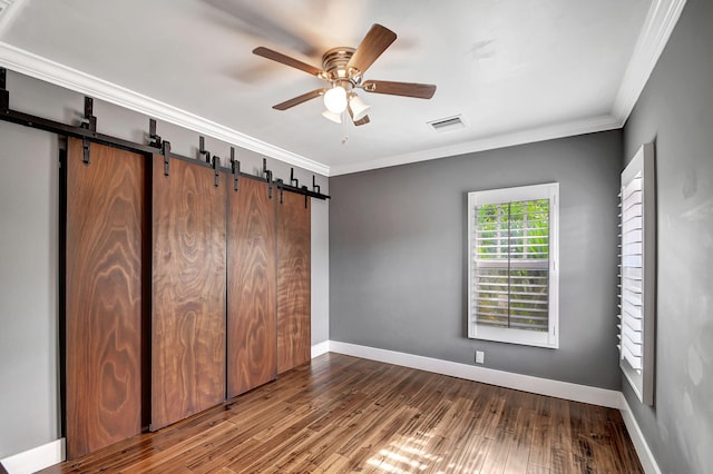 unfurnished bedroom with wood-type flooring, a barn door, and ceiling fan