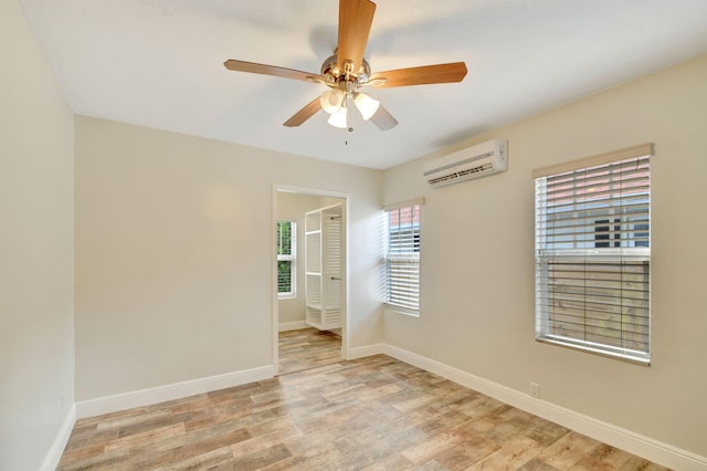 unfurnished room featuring light wood-type flooring, an AC wall unit, and ceiling fan