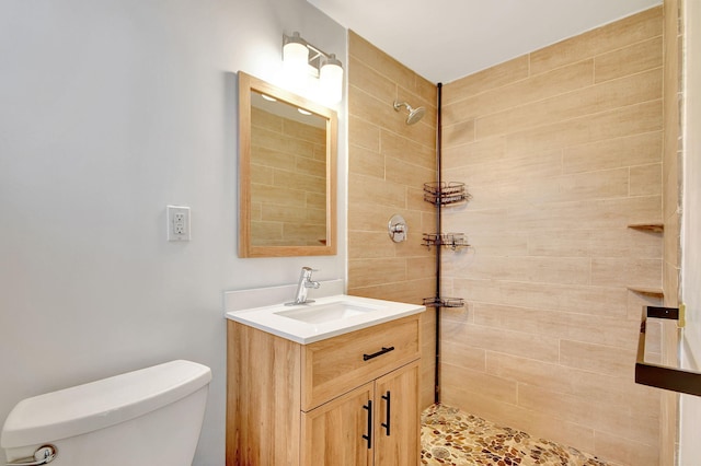 bathroom featuring tiled shower, vanity, and toilet