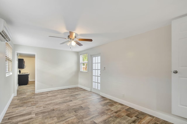 empty room featuring a wall mounted AC, ceiling fan, and light hardwood / wood-style floors