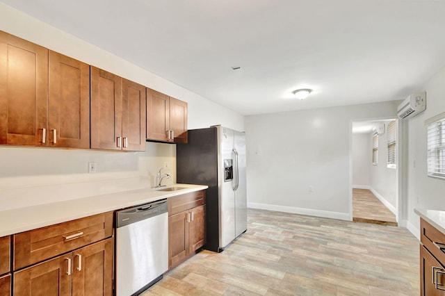 kitchen with a wall unit AC, sink, light hardwood / wood-style flooring, and appliances with stainless steel finishes