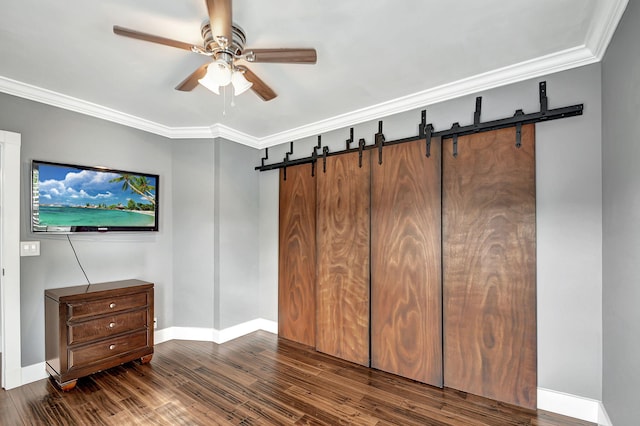 bedroom featuring ceiling fan, a barn door, dark hardwood / wood-style floors, ornamental molding, and a closet