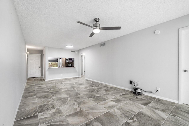 unfurnished living room featuring ceiling fan and a textured ceiling