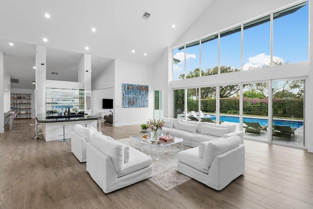 living room with hardwood / wood-style flooring, a healthy amount of sunlight, and high vaulted ceiling