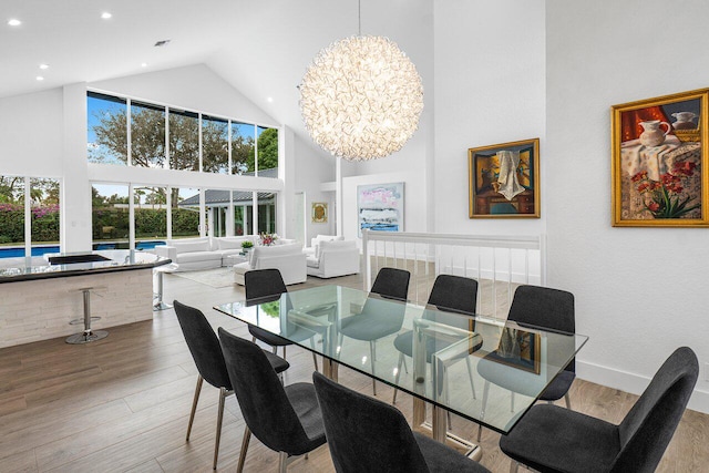 dining area featuring high vaulted ceiling, a notable chandelier, and light wood-type flooring