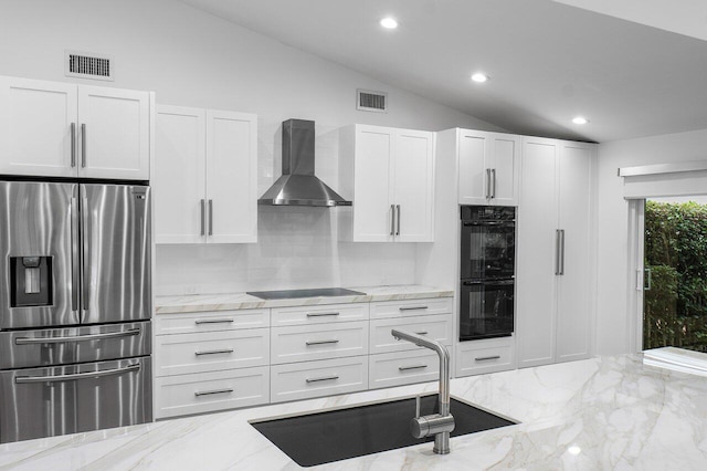 kitchen with white cabinetry, sink, wall chimney range hood, vaulted ceiling, and black appliances